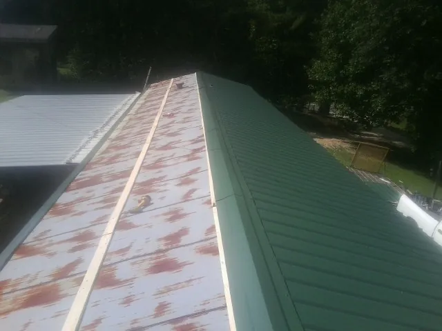 Old rusted panels beside newly installed green metal roofing — Wind Damage Roof Repair by Roofing Brothers in Darby