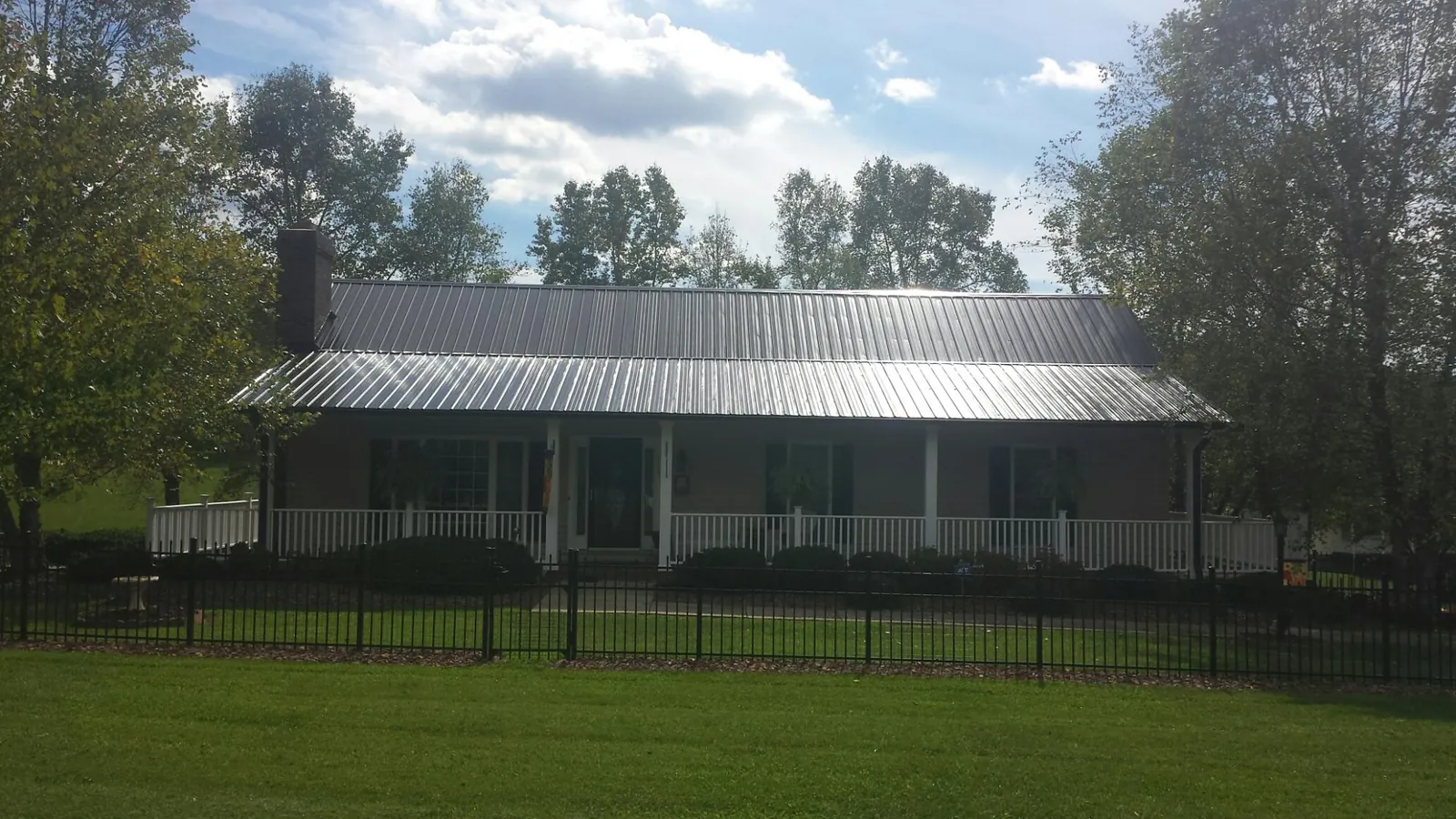 Gray metal roof on a brick ranch with a full width front porch — Gutter Guard Installation work by our crew in Darby