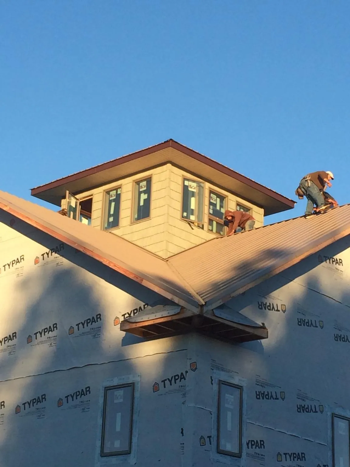 Roofers working around a rooftop cupola on a new metal roof at sunset — Roof Waterproofing in Darby by Roofing Brothers